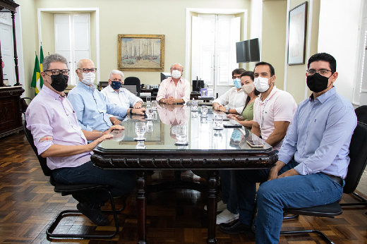 Imagem: Oito pessoas, sendo sete homens e uma mulher, sentadas em volta de uma mesa, durante reunião no Gabinete do Reitor (Foto: David Motta/UFC)