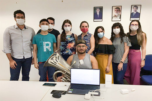 Imagem: Professores, alunos e músicos estão envolvidos na pesquisa. Na imagem, da esquerda para a direta, estão: Prof. Alex Grangeiro, Rafael Mendes, Lucas Chaves, Ana Cecília Carvalho, Profª Adeline Stervinou, Rebeca Paiva, Carolina Rossi, Profª Eva Cristino, e Henrique Pinheiro, com a tuba, testando o aparelho (Foto: Divulgação)