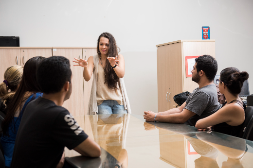 Imagem: Alunos em sala de aula assistem a uma professora falar em libras