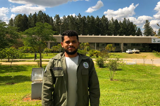 Imagem: jovem de pele negro posa para câmera; ao fundo, campo verde