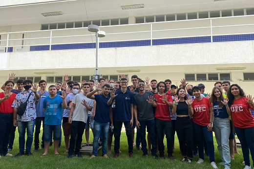 Imagem: Alunos do curso de Ciência da Computação reunidos e fazendo sinal de cinco com as mãos