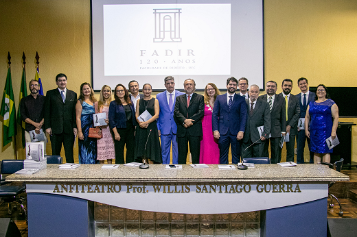 Imagem: Corpo docente da faculdade de Direito posa no anfiteatro Willis Guerra com o livro comemorativo. O reitor Cândido Albuquerque está ao centro. (Foto: Ribamar Neto/ UFC Informa)