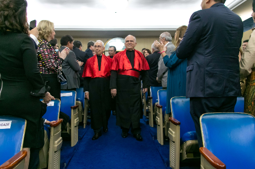 Imagem: professores homenageadas entram no auditório da Reitoria lotado