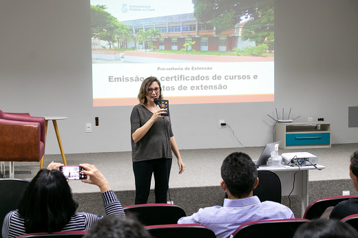 Imagem: mulher branca de cabelos loiros apresenta slides numa reunião