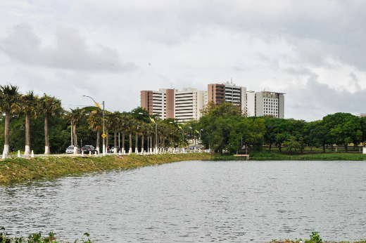 Imagem: Panorama de uma área do Campus do Pici, próxima ao açude Santo Anastácio; na imagem é possível ver o açude e uma avenida que passa ao lado do açude, com alguns carros passando (Foto: Ribamar Neto/UFC)