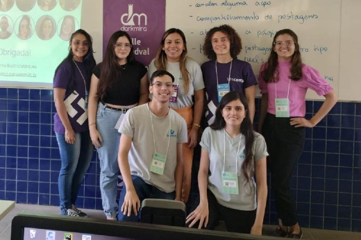 Imagem: grupo de estudantes jovens em ambiente de sala de aula, com quadro branco ao fundo.