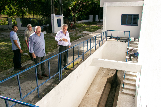 Imagem: quatro homens observam prédio branco