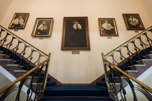 Imagem: Mostra tirada de baixo para cima mostra parte da galeria de quadro dos ex-reitores da UFC. Ao centro, o retrato do reitor Martins Filho (Foto: Júnior Panela/UFC Informa)