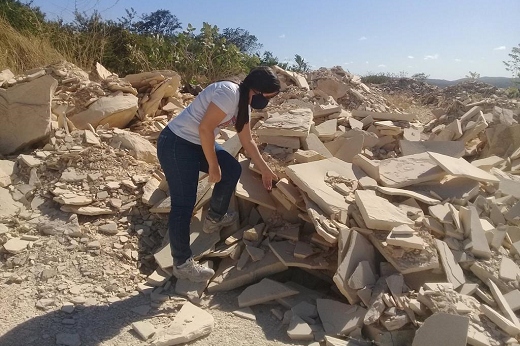 Imagem: Mulher observa e toca em placas de pedra cariri postas no chão