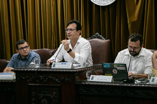 Imagem: Reitor Custódio Almeida (ao centro, de camisa branca) fala aos conselheiros no plenário do CONSUNI. (Foto: Ribamar Neto/ UFC Informa)