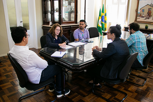 Imagem: Sentados à mesa, no Gabinete da Reitoria, estão o reitor Custódio Almeida (na cabeceira), a secretária Mitchelle Meira (à esq. dele) e assessores. (Foto: Ribamar Neto/UFC Informa)