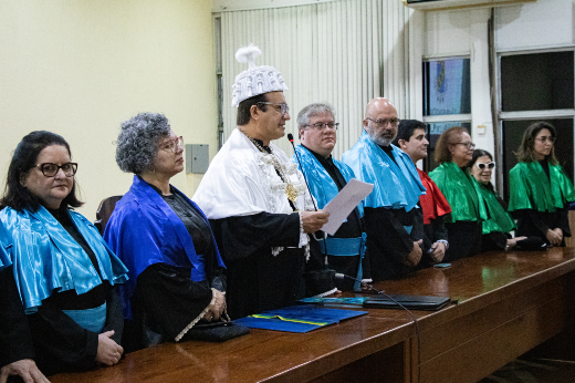 Imagem: o reitor, a vice-reitora, pró-reitores e professores compondo a mesa da cerimônia, no palco