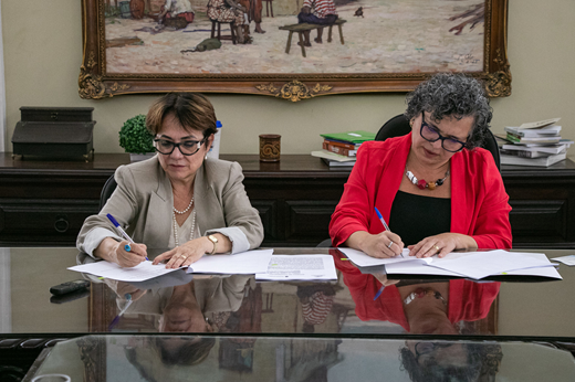 Imagem: Sentadas à mesa, Isolda Costa (IPEN) e a vice-reitora Diana Azevedo (UFC) assinam termo de cooperação técnica (Foto: Ribamar Neto/ UFC Informa)