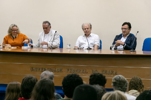 Imagem: quatro pessoas sentada em mesa de auditório 