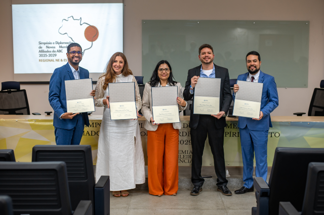 Imagem: foto de cinco pessoas em pé segurando um diploma