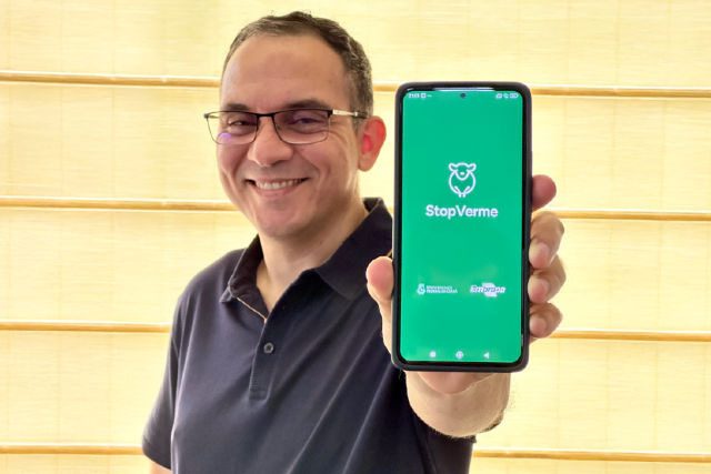 O professor da UFC Iális Cavalcante, coordenador da pesquisa, mostra a versão mais recente do aplicativo. Disponível para sistema Android, ele já conta com mais de 500 downloads (Foto: arquivo pessoal) Imagem: homem de óculos e camisa polo preta posa para foto mostrando a tela de um telefone celular, onde, sobre um fundo verde, lê-se os nomes StopVerme e Embrapa e a sigla da Universidade Federal do Ceará