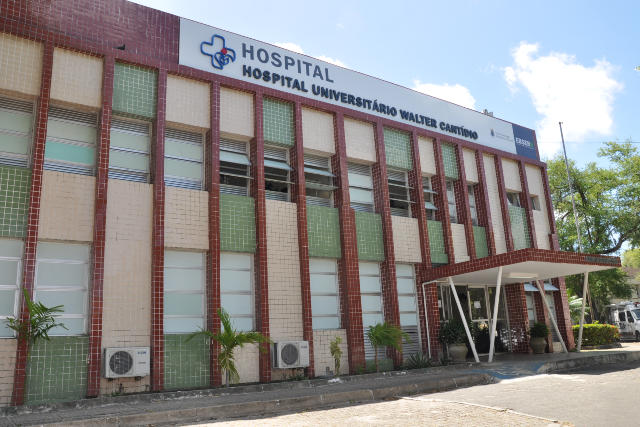 Imagem: fachada dos prédio do hospital em cores marrom claro e escuro, céu azul.