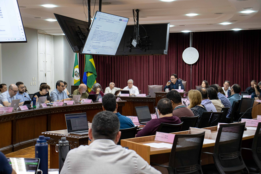 Imagem: Vista do plenário do Conselho Universitário mostra os conselheiros sentados em bancadas, com o reitor ao centro