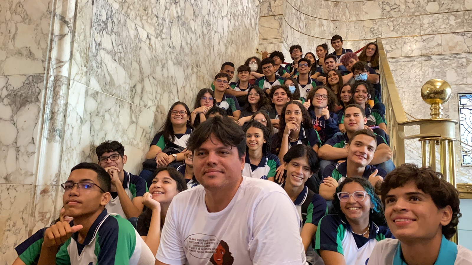 Imagem: professor Geová de Alencar posando para foto com alunos de ensino médio dentro do Cineteatro São Luiz